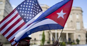 Eduardo Clark holds American and Cuban flags across the street from the Cuban embassy in Washington, D.C., U.S., on Monday, July 20, 2015. A diplomatic freeze that stretched five decades, outlasting the Cold War and nine U.S. presidencies, formally ends Monday when Cuba and the U.S. reopen embassies. Cuban Foreign Minister Bruno Rodriguez will attend a flag-raising ceremony at the Cuban chancery in Washington before meeting Secretary of State John Kerry, who will travel to Havana at a later date. Photographer: Andrew Harrer/Bloomberg via Getty Images